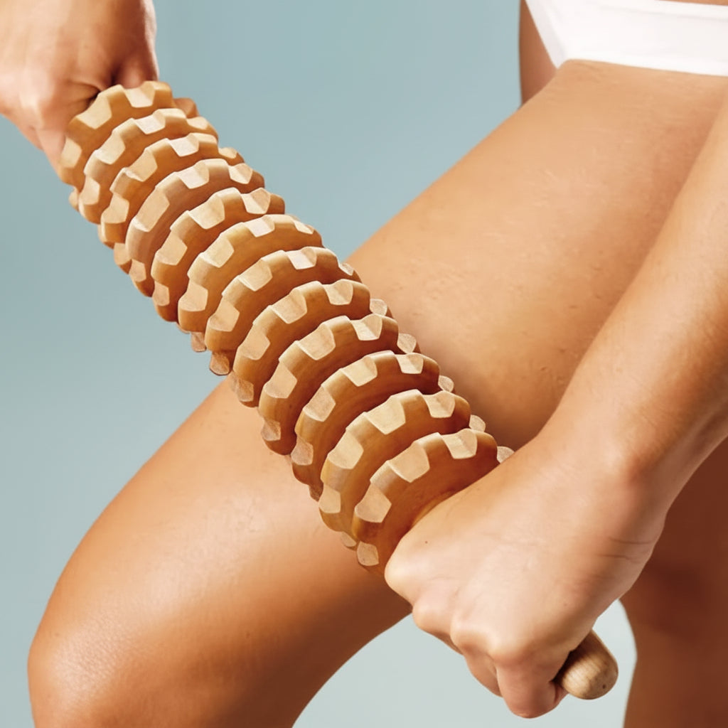 A close-up of a person using a wooden leg massager roller on their thigh, with hands gripping the handle against a light blue background.