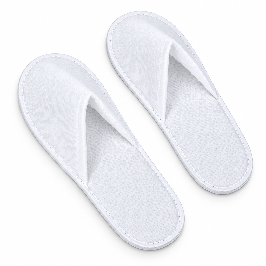 A pair of white cotton slip-on slippers with a stitched trim, shown on a plain white background.
